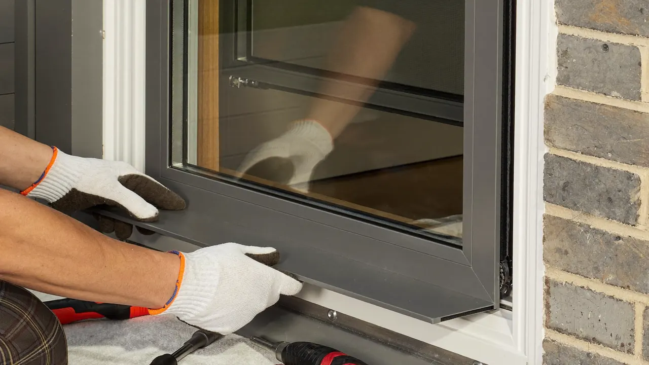 Installer fitting a white uPVC window into a brick home